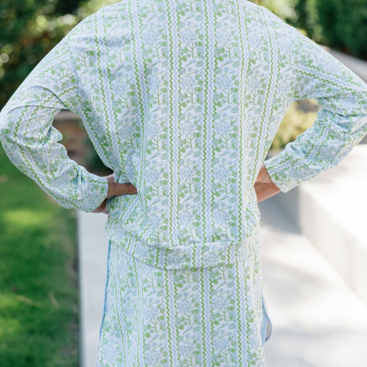 Woman wearing a green and white patterned kimono-style garment outdoors.