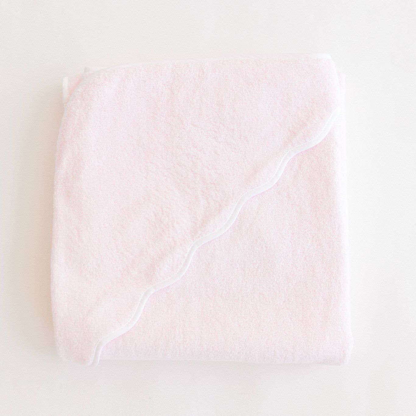 Pink Terrycloth Hooded Towel with white scallop edge on a light beige background