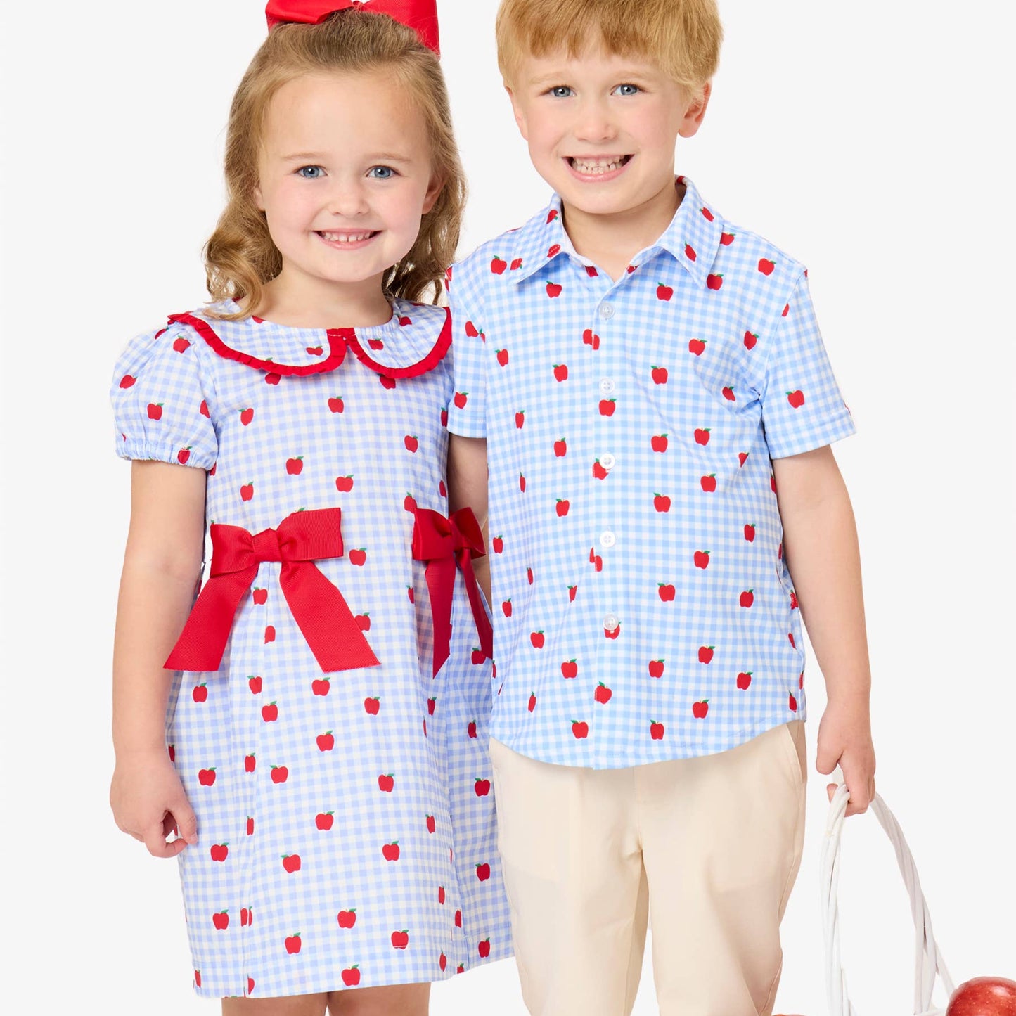 Two children, a girl and a boy, wearing matching outfits with red and blue patterns on a white background.
