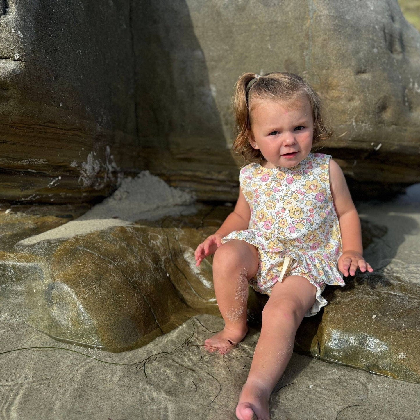Child sitting on rocks at a beach