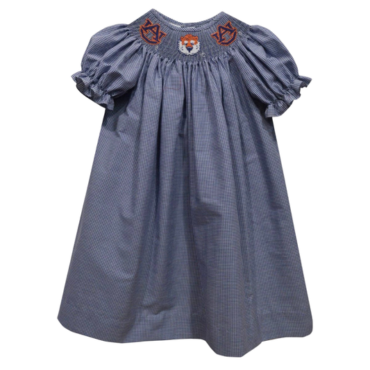 A baby girl's smocked dress in a blue and white gingham pattern, featuring puff sleeves and embroidered details on the chest including a central fox face and 'NY' monograms.