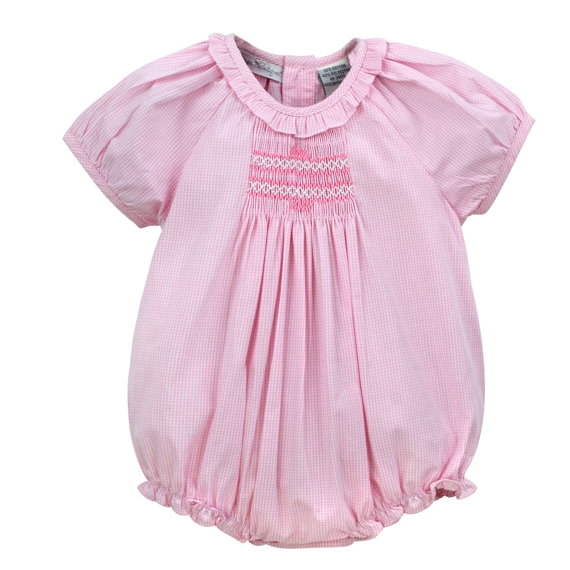 Pink baby romper with smocked details on a white background