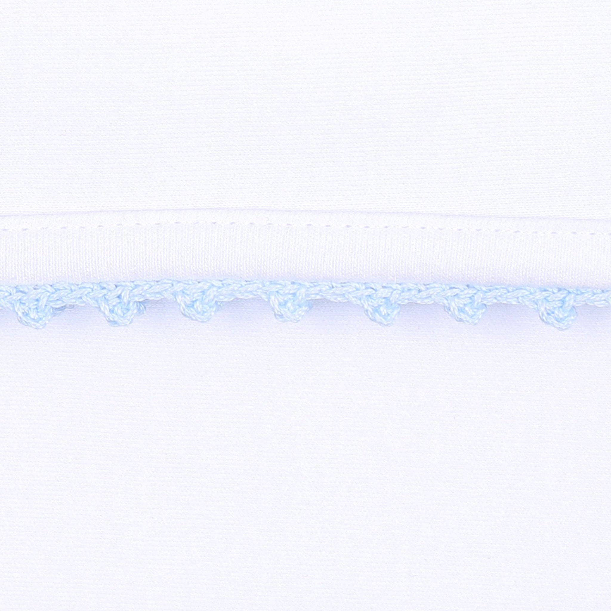 Baby boy white hat with blue crochet trim on  white background 
