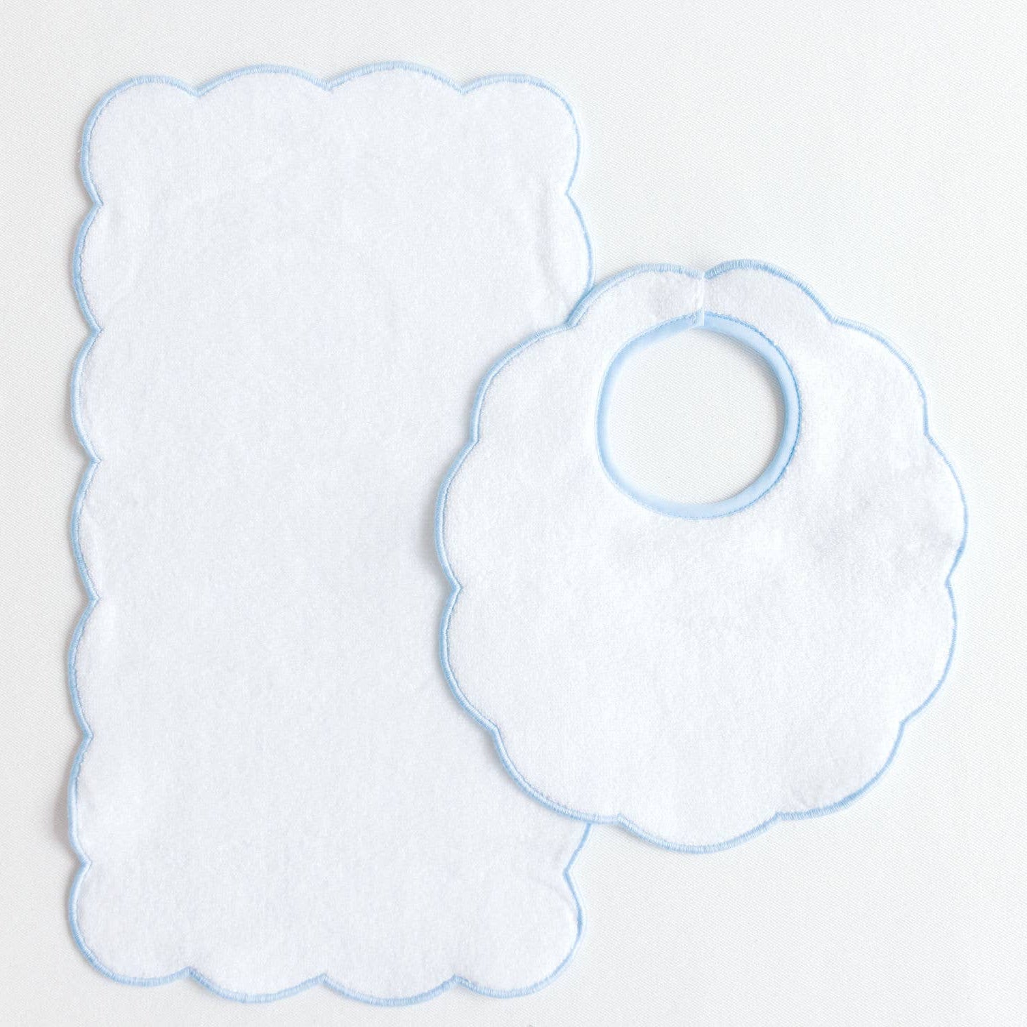 Two baby bibs with scalloped edges on a light gray background
