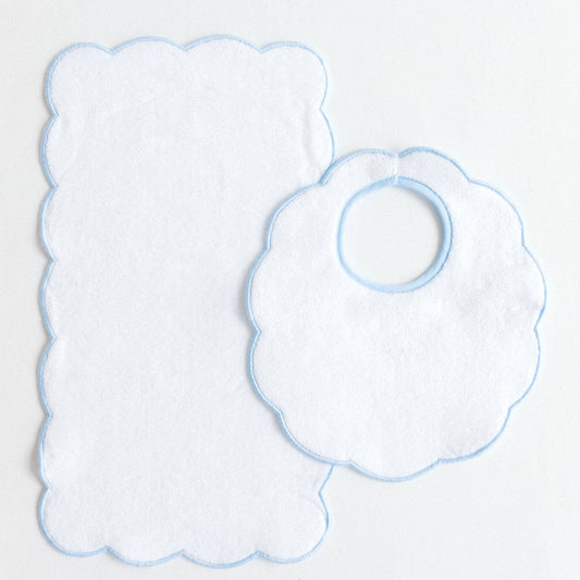 Two baby bibs with scalloped edges on a light gray background