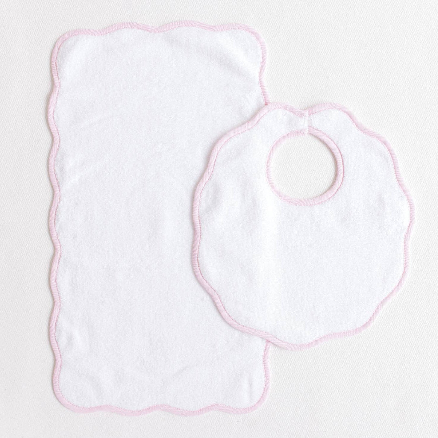 Baby bib and burp cloth set on a light pink background