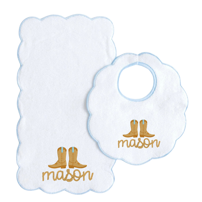 A white baby bib and matching washcloth set with scalloped edges, light blue borders, and gold embroidered cowboy boots and the name 'mason'.