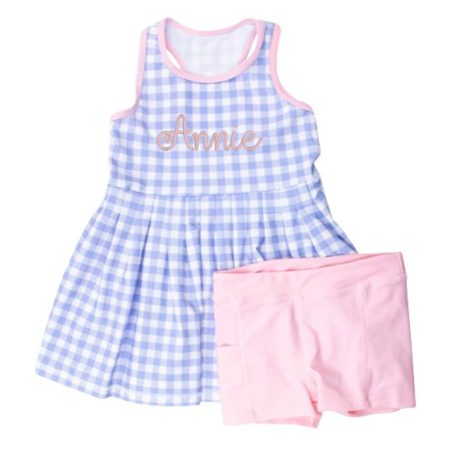 Children's outfit with blue checkered dress and pink shorts on a white background