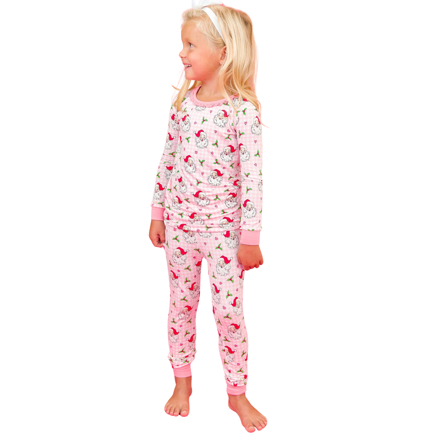 Young girl wearing a pink pajama set with cherry design on a white background