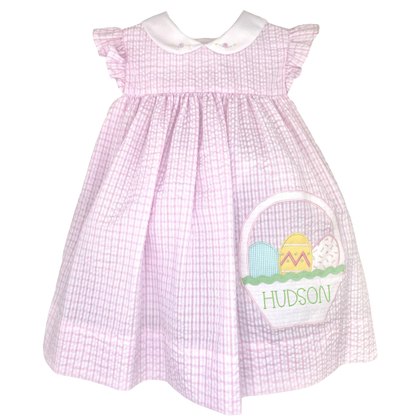 Pink checkered dress with Easter basket design and 'Hudson' text on a white background