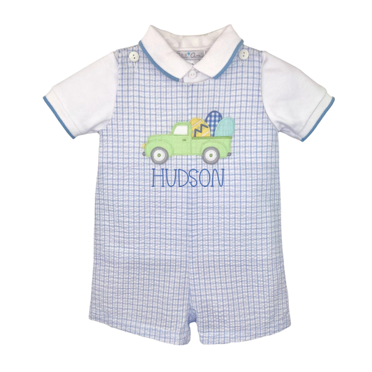 Baby romper with checkered pattern and embroidered truck design on a white background