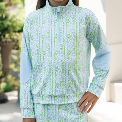 Child wearing a light blue and green patterned outfit outdoors.