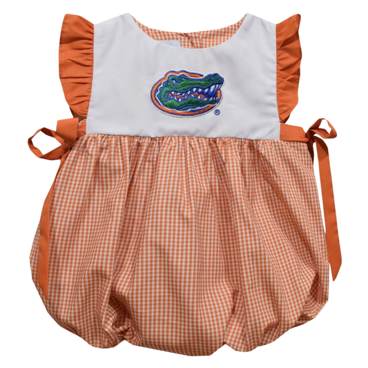 A baby romper featuring a white bib-style top with orange ruffle sleeves and side ties, and a peach-and-white gingham bubble skirt. The center chest has an embroidered Florida Gators alligator logo.