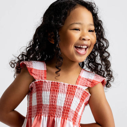Young girl wearing a red and white checkered dress against a plain background