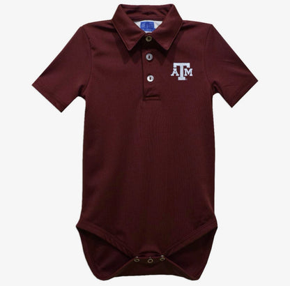 A baby short-sleeve polo bodysuit in maroon with a white embroidered 'A&M' logo on the left chest, featuring a three-button placket and snap closures at the crotch.