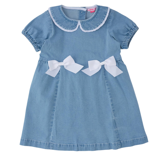 A light blue denim baby dress with a white Peter Pan collar, short puff sleeves, and two white satin bows at the waist, shown against a plain white background.