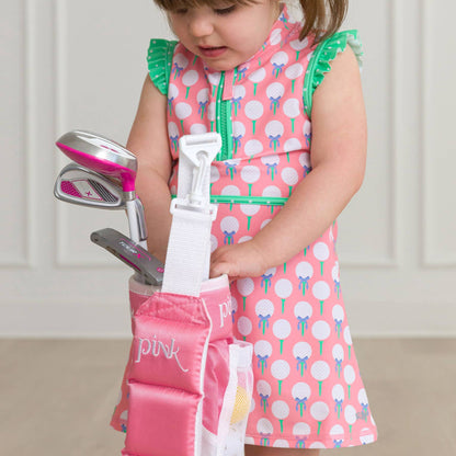 Child in a pink dress with golf clubs and accessories