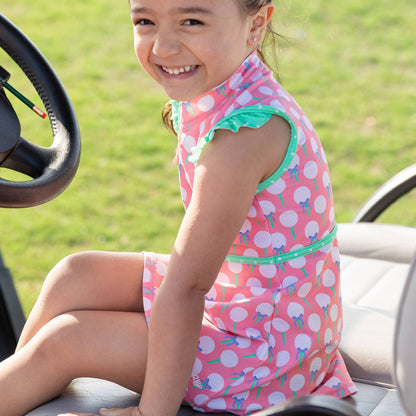 Young girl in a pink polka dot dress with a bow sitting on a golf cart.