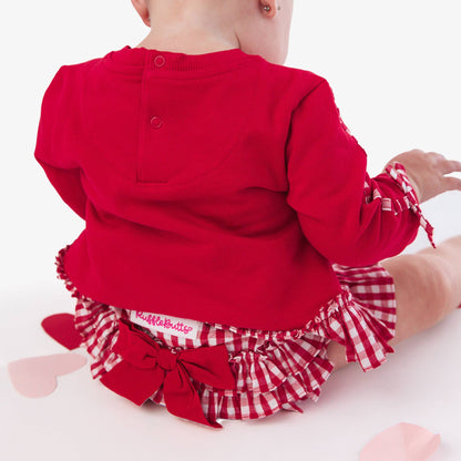 Baby in red outfit with checkered bloomers on a white background