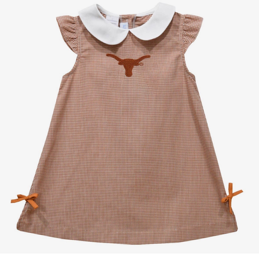 A toddler girl's sleeveless dress featuring a burnt orange and white gingham pattern, a white Peter Pan collar, an embroidered orange longhorn logo on the chest, and matching orange ribbon bows at the bottom corners.