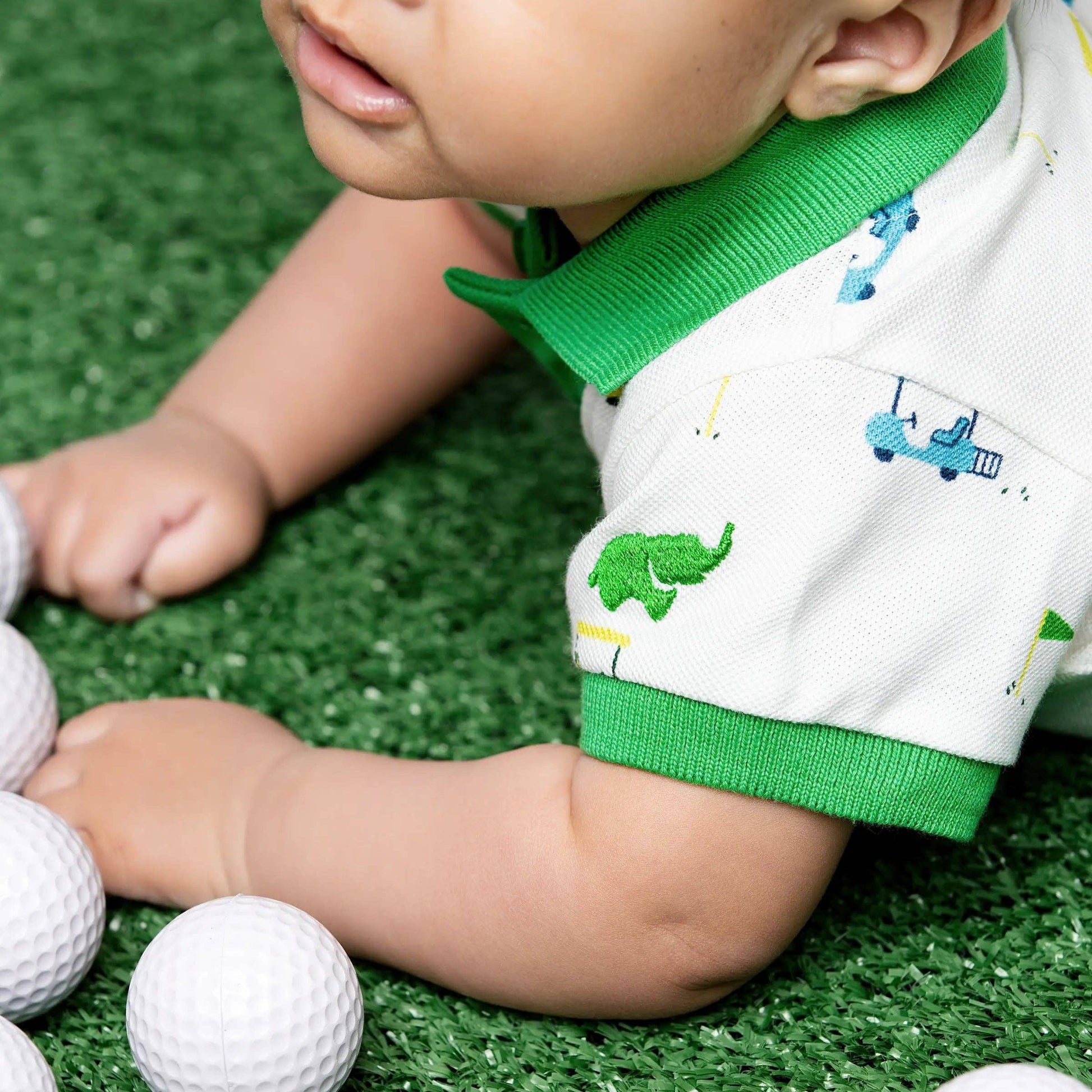 Baby playing with golf balls on a grass-like surface