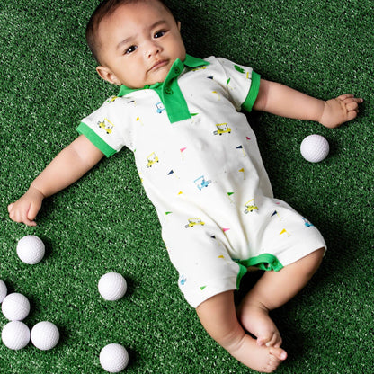 Baby lying on a green surface in romper with golf print with white golf balls around