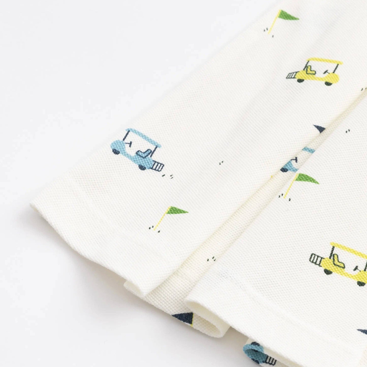 White dress with colorful golf carts on a white background detail of the skirt of the dress