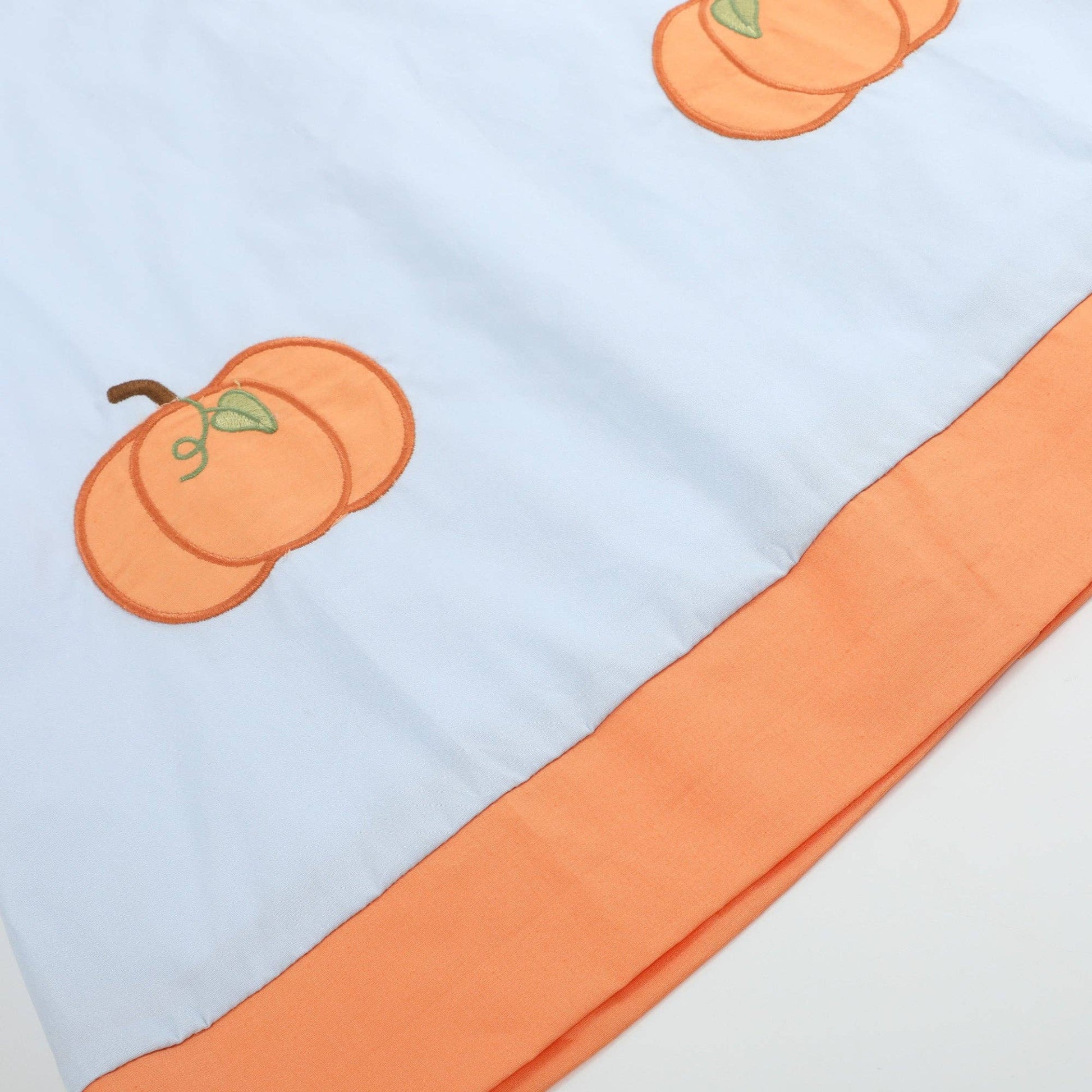 Baby blanket with orange pumpkin designs on a light blue background