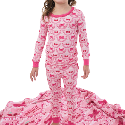Child wearing pink pajamas with bow and cherry pattern on a white background