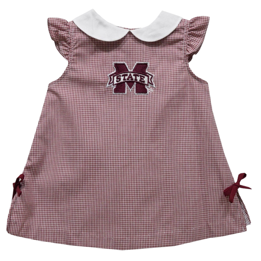 A toddler girl's gingham dress in maroon and white with a white Peter Pan collar, ruffled cap sleeves, side bows, and an embroidered 'MSTATE' logo on the chest.