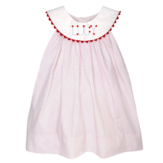White dress with red polka dots and embroidered name on a white background