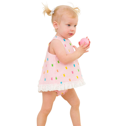 Child wearing a pink dress with colorful bunny patterns on a white background