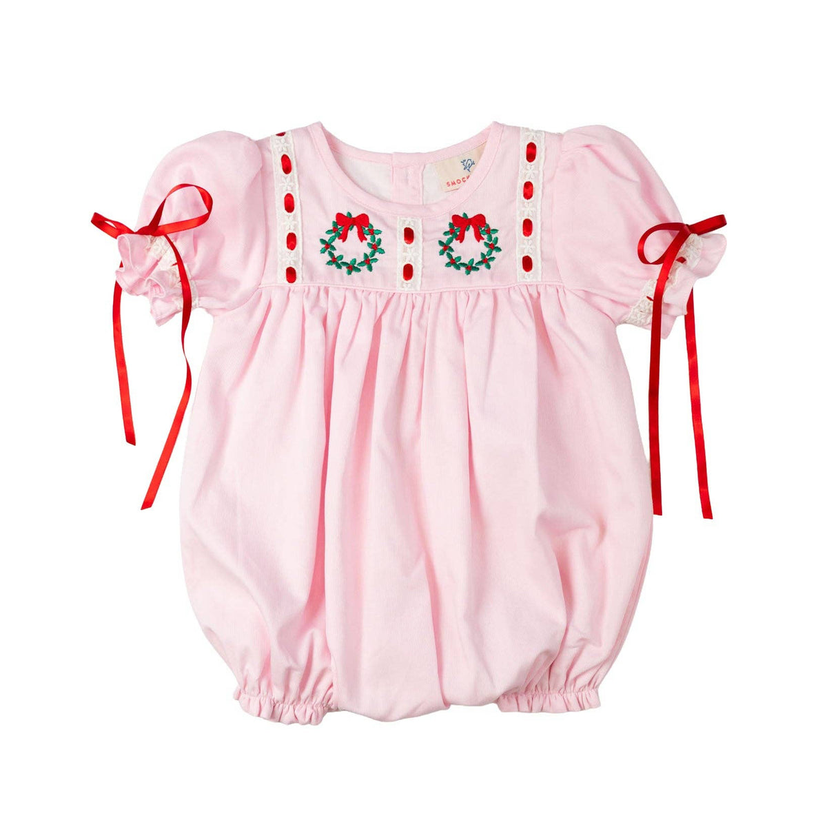 Pink baby romper with wreath embroidery and red bows on a white background