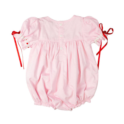 Pink baby romper with red straps on a white background