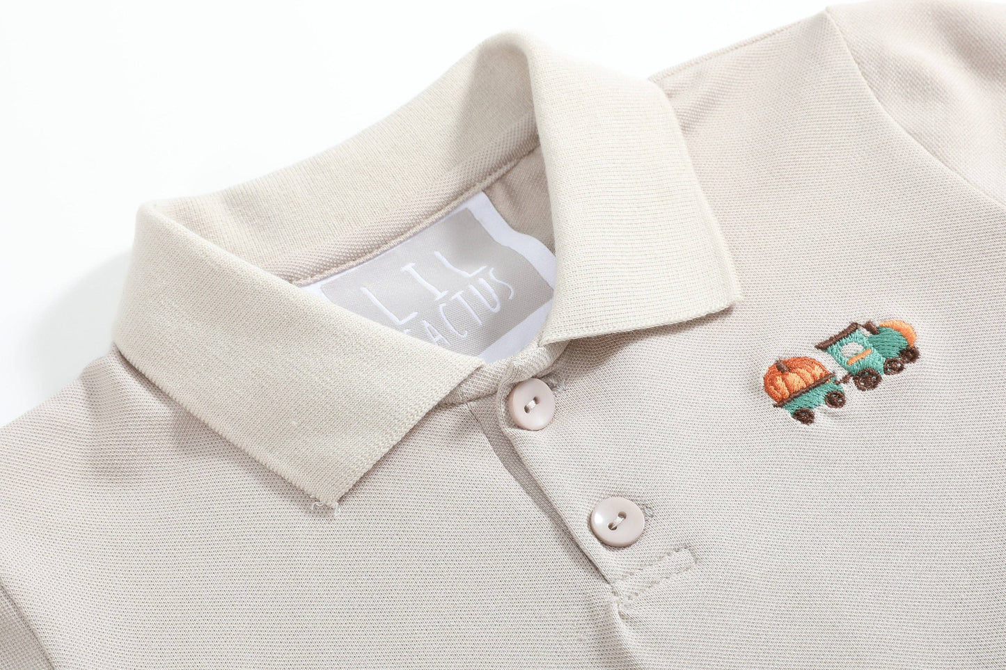 Close-up of a beige polo shirt with a small embroidered design on the chest.