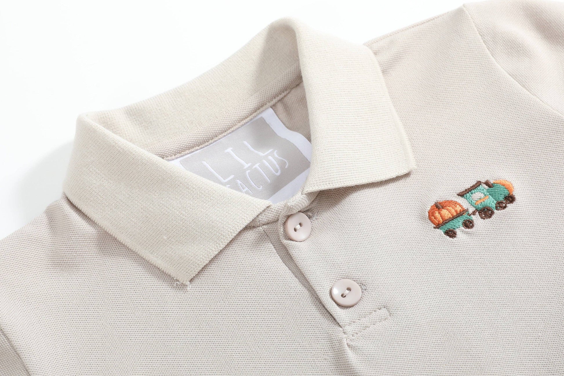 Close-up of a beige polo shirt with a small embroidered design on the chest.