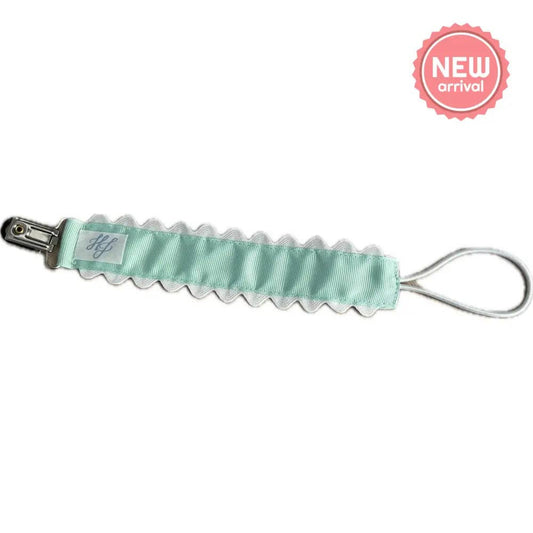 Mint green baby accessory with silver clip on a white background