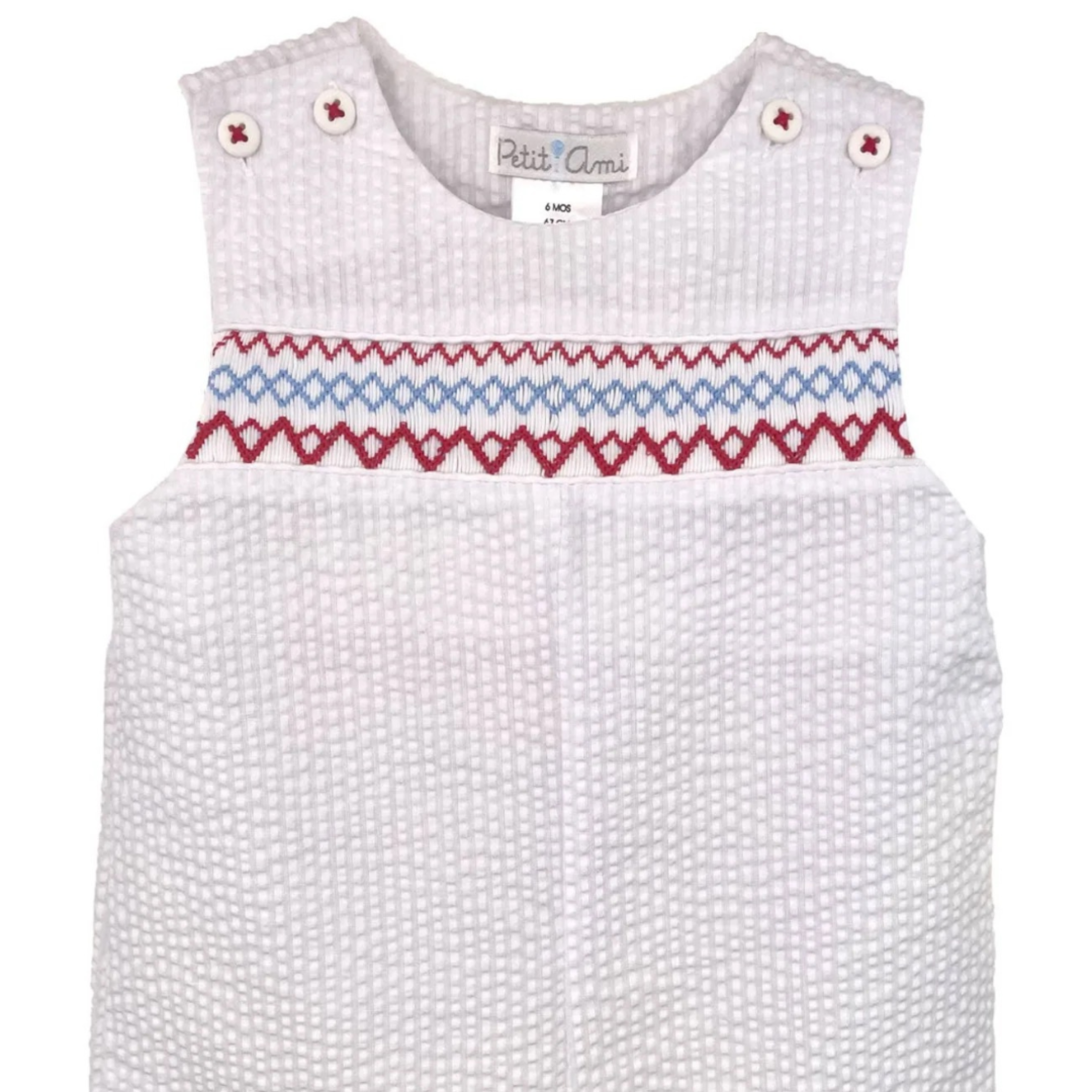 White baby romper with red and blue geometric smocking on a white background