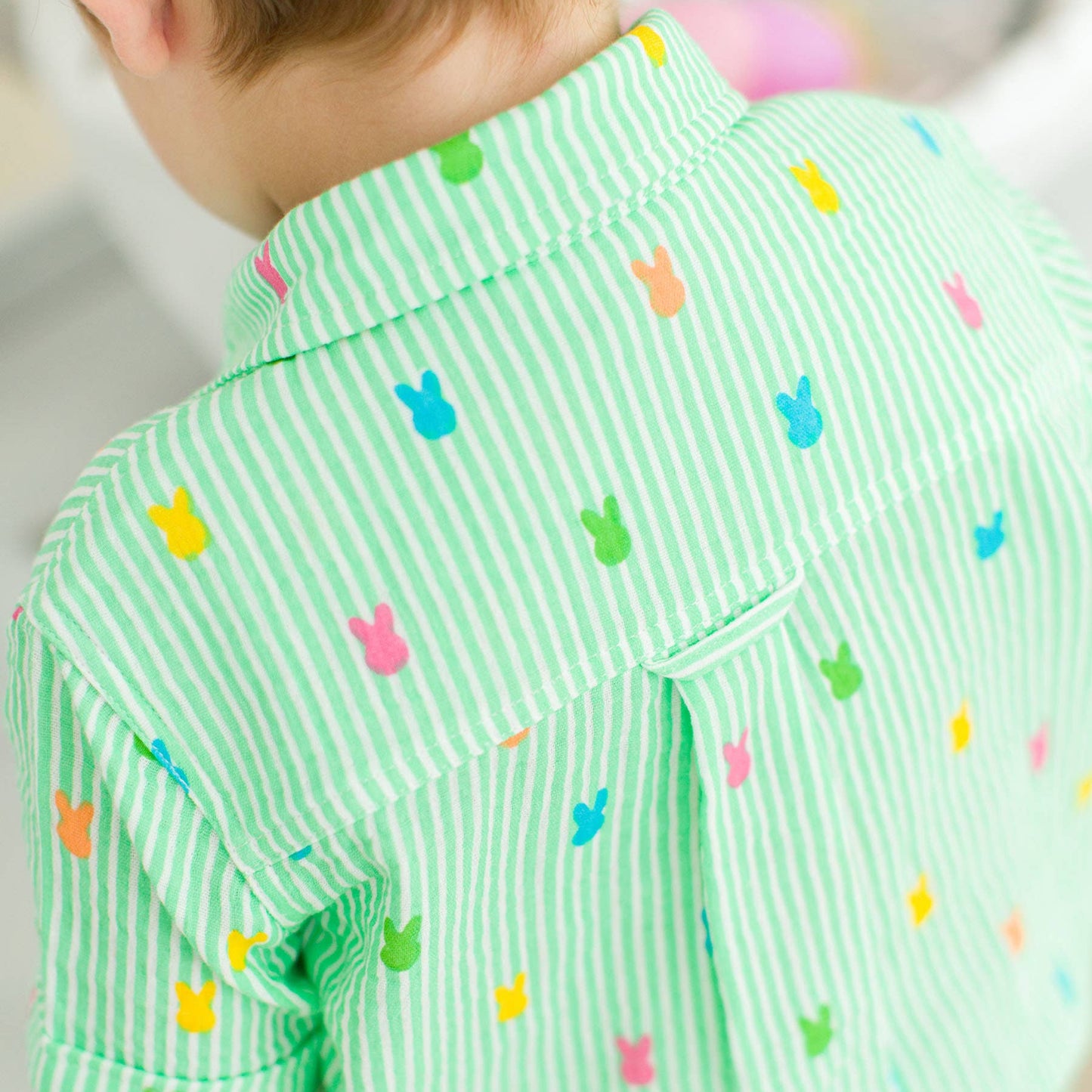 Child wearing a green striped shirt with colorful bunny patterns.